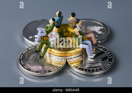 Différentes pièces de crypto-monnaies avec les gens assis sur eux. Banque D'Images