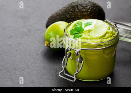 Sauce guacamole mexicain dans un pot sur fond noir en noir Banque D'Images