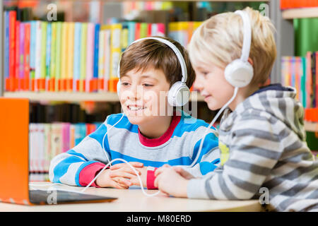 Les enfants dans une bibliothèque à l'écoute de livres audio Banque D'Images