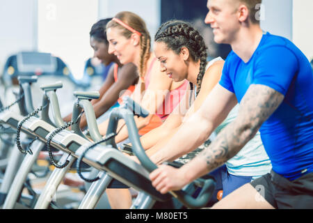 Vue latérale d'une belle femme en souriant tandis que le vélo au cours de spinning Banque D'Images