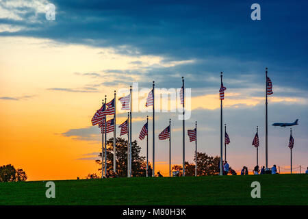 Washington D.C., USA, octobre 2016 : coucher de soleil sur agitant des drapeaux américains avec les touristes et l'atterrissage d'un avion en arrière-plan Banque D'Images