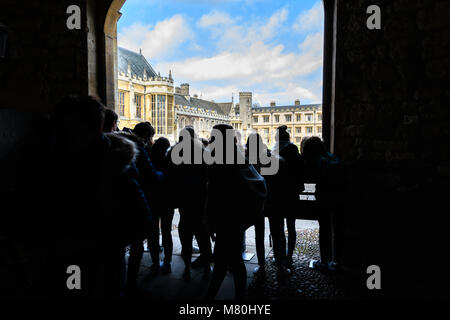 Un groupe d'étudiants dans le Queens' Gate donnant sur la grande cour du Trinity College, Université de Cambridge, Angleterre, sur une journée d'hiver ensoleillée. Banque D'Images