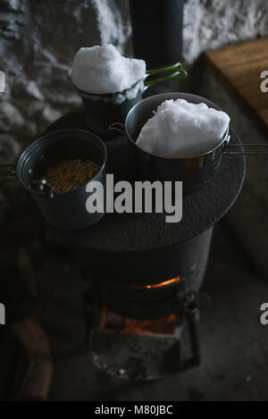 La fonte de la neige pour l'eau sur un poêle à bois dans un refuge de montagne Banque D'Images