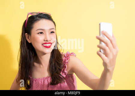 Femme d'été prenant photo selfies sur fond jaune. Banque D'Images