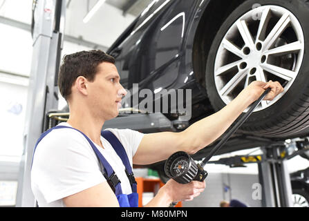 Mécanicien auto vérifie la pression d'air d'un pneu dans le garage Banque D'Images