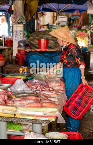 Une femme portant un chapeau conique traditionnel bambou organise la vente de poisson elle est au marché couvert à Hoi An, Vietnam Banque D'Images