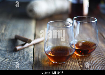 Outils de vintage verre de rhum sur une table en bois rustique avec des cigares et bouteille.barbier sur fond de bois Banque D'Images