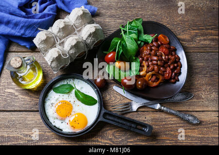 La casserole d'œufs frits, haricot mijotée dans une sauce tomate et d'épinards frais. Concept d'un petit-déjeuner sain. Banque D'Images