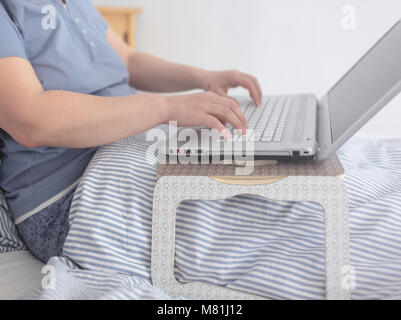 Femme travaillant avec un ordinateur portable dans le lit Banque D'Images