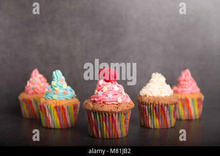 Des cupcakes avec glaçage coloré et des fruits Banque D'Images