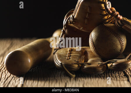 Close up image d'une vieille base-ball, batte de baseball, et un gant de baseball sur table en bois en arrière-plan noir Banque D'Images