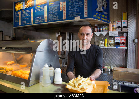 Homme turc servant de jetons à un restaurant de poisson et frites à emporter Banque D'Images