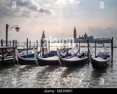 L'Italie, en hiver : la neige sur les gondoles de la Place Saint Marc, Venise, avec l'île de San Giorgio Maggiore en arrière-plan. Banque D'Images