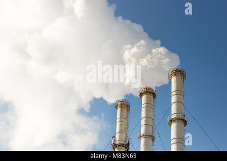 Fumeurs tuyaux nuages contre fond de ciel bleu. La contamination de l'air dioxyde de carbone. La pollution de l'environnement Banque D'Images