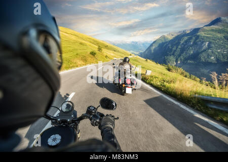 POV de motorbiker maintenant le bar, équitation dans Alpes en beau coucher du soleil Ciel dramatique. Et la liberté de déplacement, activités en plein air Banque D'Images