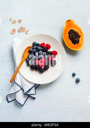 Le petit-déjeuner avec les petits fruits, yaourts, flocons et couper la papaye dans une assiette sur la table. matin sain Banque D'Images