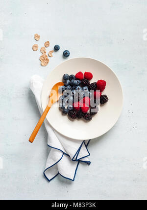 Le petit-déjeuner avec les petits fruits, yaourts, flocons et couper la papaye dans une assiette sur la table. matin sain Banque D'Images