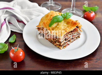 Lasagne à la viande fraîche, des lasagnes à la bolognaise, un plat de pâtes sur une table en bois avec des feuilles de basilic. La cuisine italienne. Banque D'Images