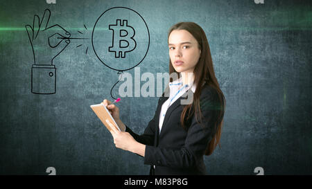 Successful business woman standing près de btc logo. Elle doit acheter ou vendre Bitcoin. Concept d'criptocurrency virtuel. Banque D'Images