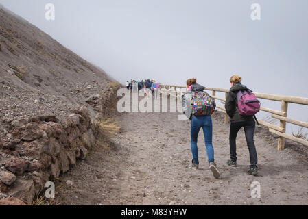 Vésuve gens touristes, vue arrière de deux jeunes femmes portant des sacs à dos marchant sur le sentier menant au sommet du Vésuve, Italie. Banque D'Images