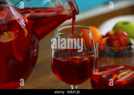 Cocktail Sangria avec des fruits frais dans un bocal en verre est versé dans un verre Banque D'Images