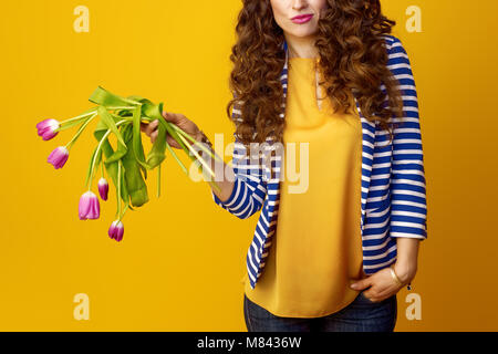 Triste jeune femme en blouson rayé sur fond jaune fleurs fanées holding Banque D'Images