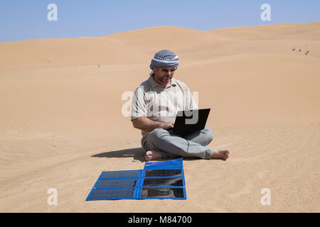 un homme utilise son ordinateur portable près d'un panneau solaire portable, mettant en évidence le travail à distance et la durabilité en mettant l'accent sur l'autonomie, le travail à distance Banque D'Images