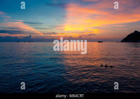 Coucher de soleil incroyable avec la moitié de la moitié de l'orange-jaune et bleu et rose ciel au-dessus de la mer. Voir l'île de Nang Yuan de Ko Tao, avec buoyants dans l'eau Banque D'Images