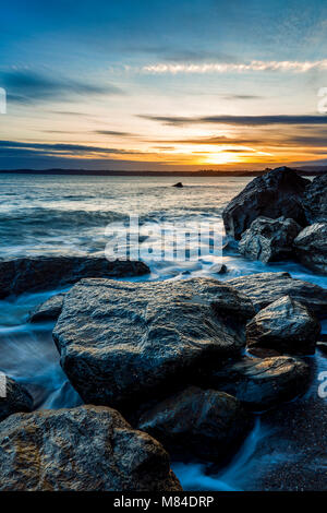 Coucher du soleil le jour se ferme à l'égard de l'énorme rochers au Polerris Beach à Cornwall. La vue sur la baie vous emmène à cracher, Crinnis, Charlestown et Banque D'Images