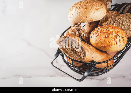 Variété de pain de grains fait maison, dans un panier métallique, blanc en arrière-plan copy space Banque D'Images