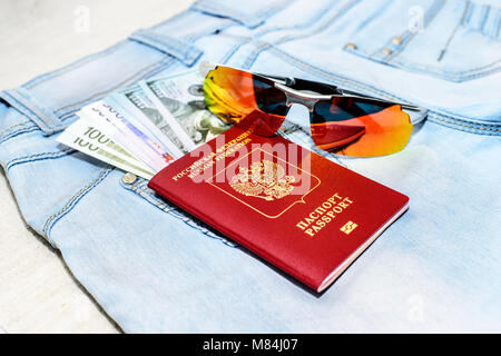 Passeport russe rouge avec de l'argent des factures, et des verres sur un jean. Le concept du voyage Banque D'Images