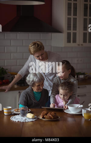 Multi-generation family using digital tablet in kitchen Banque D'Images