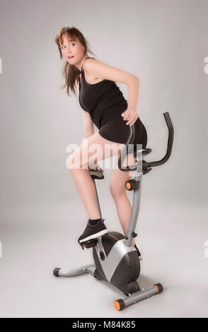 Woman riding en arrière de la bicyclette d'exercice au cours d'une séance de remise en forme Banque D'Images