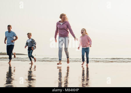 Low angle view of family fonctionnant à partir de la marée au bord de la mer. S'amuser sur leurs vacances à la plage.