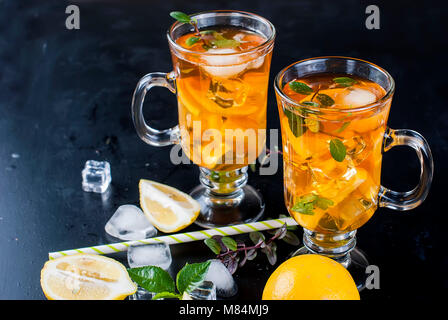 Verres de thé glacé avec les tranches de citron sur fond noir thé glacé rafraîchissant Banque D'Images