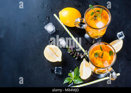 Verres de thé glacé avec les tranches de citron sur fond noir thé glacé rafraîchissant Banque D'Images