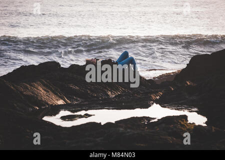 Woman lying on rock sur une plage Banque D'Images