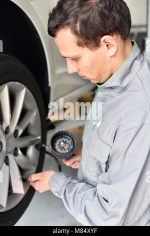 Mécanicien auto vérifie la pression d'air d'un pneu dans le garage Banque D'Images