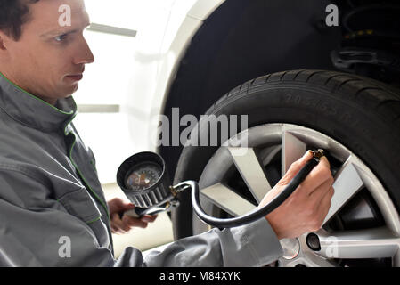 Mécanicien auto vérifie la pression d'air d'un pneu dans le garage Banque D'Images