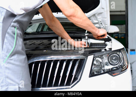 Mécanicien de voiture dans un atelier de réparation de moteur - libre et de diagnostic sur un véhicule Banque D'Images