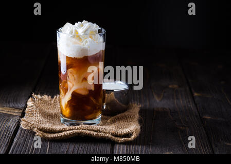 Café glacé dans un grand verre avec de la crème versée au-dessus. Banque D'Images