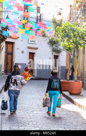 Les mexicains marche sur rue pavée avec lit suspendu au-dessus des drapeaux bannière colorée Banque D'Images