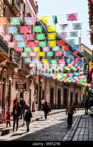 Les mexicains marche sur rue pavée avec lit suspendu au-dessus des drapeaux bannière colorée Banque D'Images