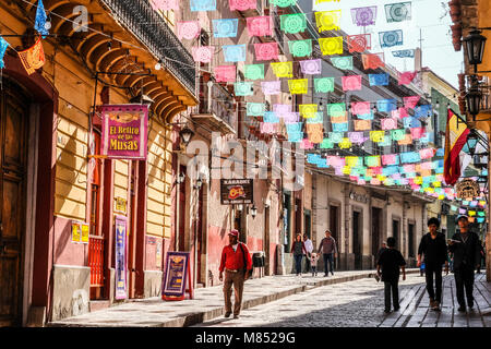 Les mexicains marche sur rue pavée avec lit suspendu au-dessus des drapeaux bannière colorée Banque D'Images