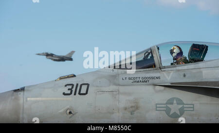 Un F-16 Fighting Falcon affecté à la 13e Escadron de chasse décolle comme lieutenant de la Marine américaine Garrett Sherwood, un Strike Fighter Squadron (VFA) 115 F/A-18E Super Hornet pilote, se prépare à taxi à Misawa Air Base, Japon, le 28 février 2018. VFA-115, qui a récemment déménagé à Iwakuni Marine Corps Air Station de Naval Air Facility Atsugi, a effectué une sortie anti-aériennes défensives aux côtés de pilotes de F-16. (U.S. Photo de l'Armée de l'air par le sergent. Deana Heitzman) Banque D'Images