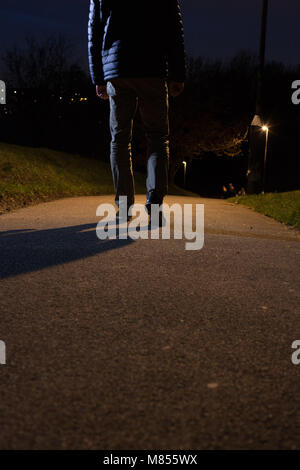 Vue arrière d'un homme marchant dans la distance. La partie inférieure du corps. Banque D'Images