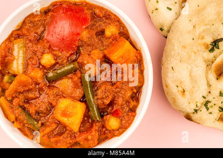 Le style indien Masala curry végétarien contre un fond rose avec du pain naan Banque D'Images