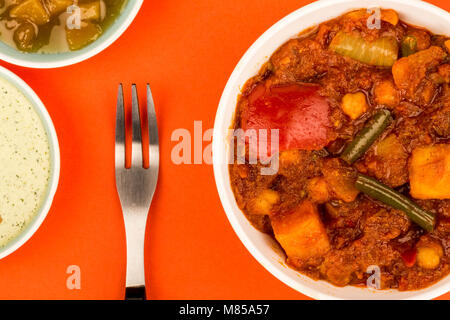 Le style indien Masala curry végétarien sur un fond rouge avec Chutney de mangue et Sauce Banque D'Images