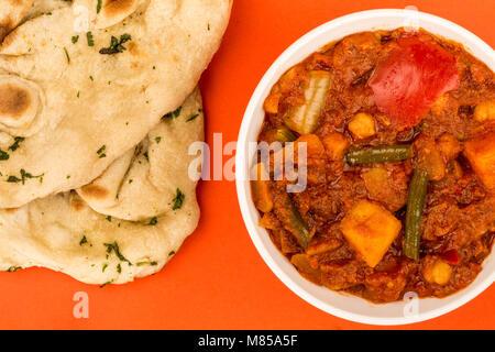 Le style indien Masala curry végétarien sur un fond rouge avec du pain naan Banque D'Images