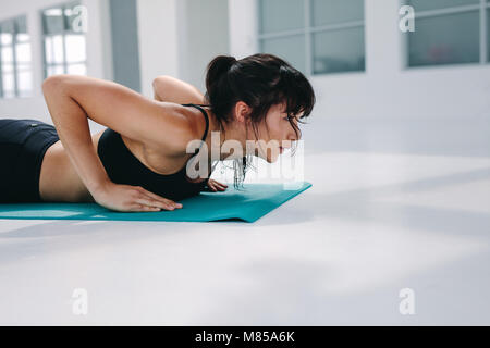 Femme forte faisant des pompes dans la salle de gym. femme de fitness s'entraînant sur tapis de yoga dans le club de santé. Banque D'Images